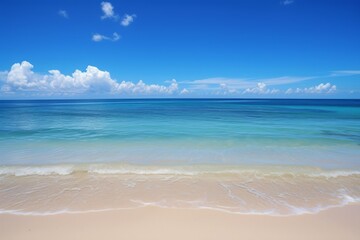 Fototapeta premium Beautiful beach scene with clear blue sky and white clouds, suitable for travel brochures, vacation advertisements, and peaceful backgrounds.