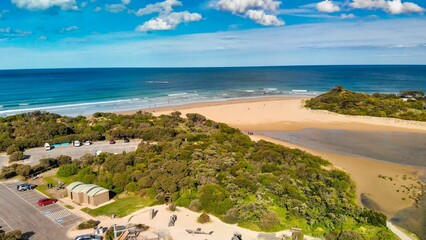 Stunning beach with mesmerizing blue waters and rocky vegetation covering the shore. © Wirestock