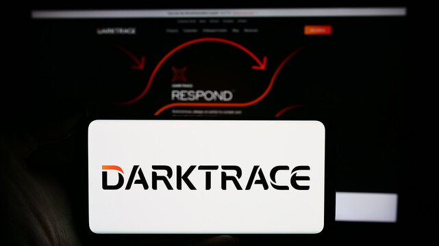 Stuttgart, Germany - 03-17-2024: Person holding cellphone with logo of British cyber security company Darktrace plc in front of business webpage. Focus on phone display.