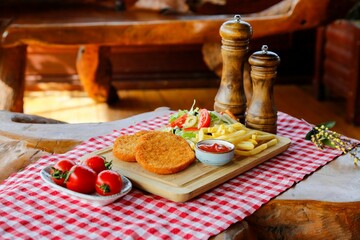 Tray with chicken nuggets, french fries and salad on a checkered tablecloth