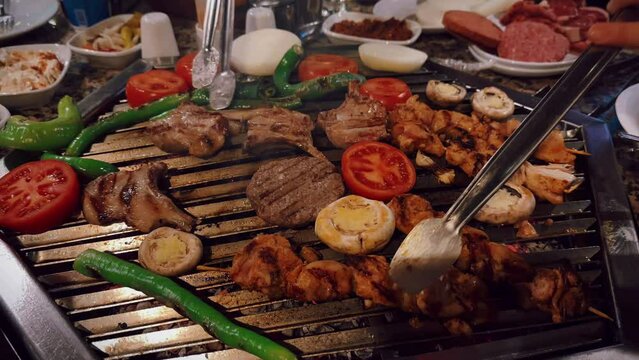 High angle of chicken and beaf meat being grilled with tomatoes, peppers and mushrooms