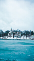 Winter scene featuring a majestic white building across a tranquil lake