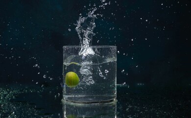 a lemon falling into a clear glass of water with a splash
