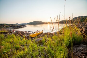 Yellow kayak on the shore of a lake during the sunset in Telemark, Norway - obrazy, fototapety, plakaty