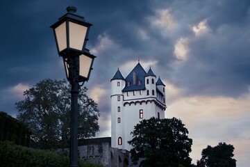 Low angle shot of a castle tower near a vintage street lamp under a gloomy sky in Eltville, Germany - obrazy, fototapety, plakaty