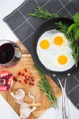 Iron pan with three eggs with herbs and spices, arranged in an aesthetically pleasing arrangement