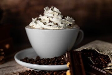 Overhead view of a white ceramic cup filled with a cappuccino with chocolate and cream