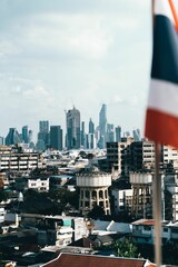 Vertical shot of the Bangkok Skyline visible from a roof with a flag