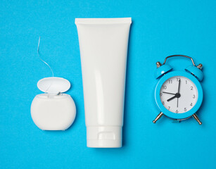 Toothpaste and dental floss on a blue background, top view