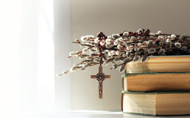 christian rosary cross, biblical books and willow branches on table, abstract light background. Orthodox palm Sunday, Easter holiday. Symbol of Christianity, Lent, Faith in God, Church. copy space