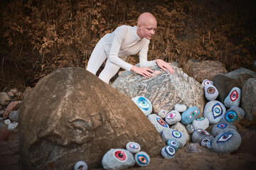 Young hairless girl with alopecia in white futuristic costume looking at surreal landscape with lot...