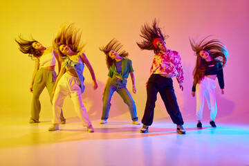Group of stylish young women dancing contemp, hip hop dance in casual clothes against gradient...