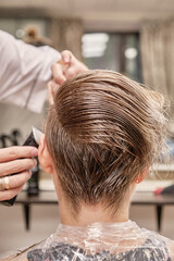Hairdresser trimming hair with electric razor or trimmer. Haircut close up. Hairstylist hairdresser...