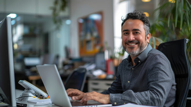 jeune homme souriant dans un bureau assis devant son ordinateur