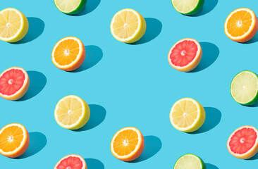 Colorful sunlight fruit pattern made of red grapefruit, orange, lime and lemon slices on light blue background with copy space. Minimal summer concept. Creative food idea. Citrus fruits aesthetic.