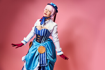 tempting sexy female cosplayer in blue hat and vibrant attire looking at camera on pink backdrop