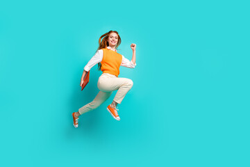 Fototapeta na wymiar Photo of cheerful adorable girl wear orange stylish clothes hurry run empty space isolated on cyan color background
