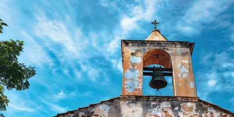 A close-up of a church bell tower against a backdrop of blue sky. - obrazy, fototapety, plakaty