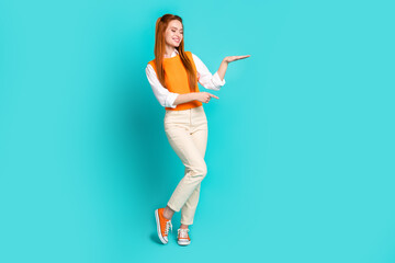 Fototapeta na wymiar Full length photo of nice cute girl wear trendy clothes demonstrates proposition empty space isolated on aquamarine color background