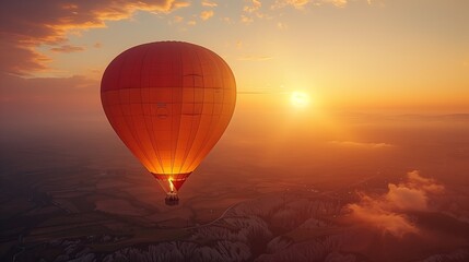 Fototapeta premium Hot Air Balloon Glowing at Sunset in Sky. Solitary hot air balloon glows radiantly against the sunset sky, floating over a vast and patterned landscape.