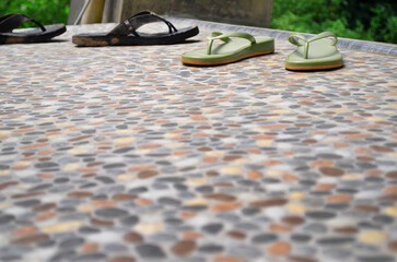 close up of outdoor terrace floor with stone pattern with two pairs of sandals