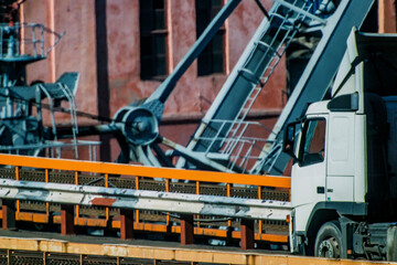 Truck driving over a bridge with cranes in the background