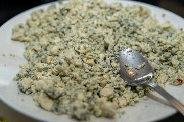 Crumbled blue cheese on a plate as a salad topping for lunch salad