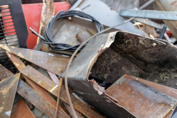 In a close-up photograph, abandoned metal waste litters a scrap yard, portraying the industrial...