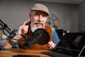 Studio podcast avec un micro et un ordinateur tablette et un homme souriant au look stylé et vintage avec une barbe hipster - 769783436