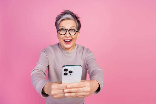 Photo of excited cheerful woman wear trendy clothes hands hold modern device apple ipone novelty isolated on pink color background