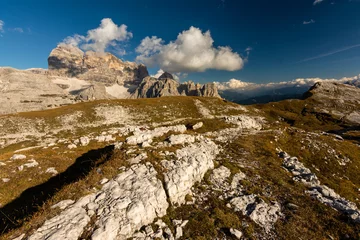 Rolgordijnen Rocky footpaths below the monumental peak of Tre Cime with the cloudy blue sky © Simona_Mach