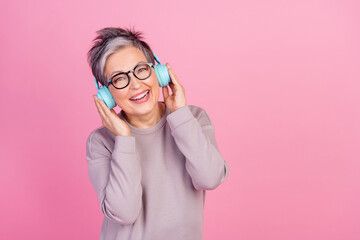 Photo of positive cheerful woman wear trendy clothes listen mp3 player songs empty space isolated on pink color background