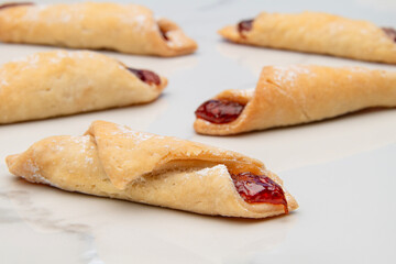 Closeup of rolled pastries filled with strawberry jam on white marble