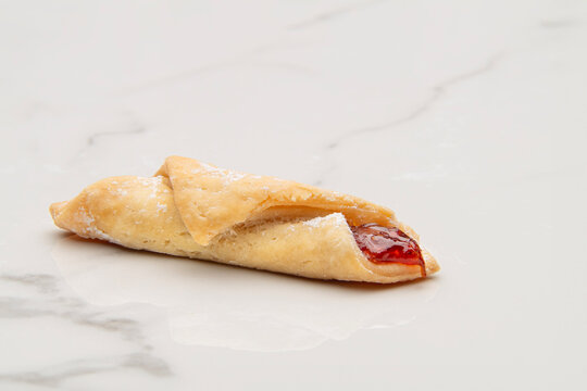 Rolled pastry puff filled with strawberry jam and coated with powdered sugar - Powered by Adobe