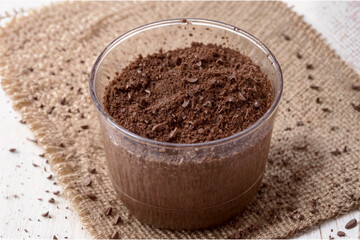 A Cup Full of Chocolate Powder Chocolate Custard A cup filled with chocolate powder chocolate custard sits on a burlap mat. - obrazy, fototapety, plakaty
