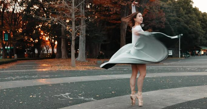 Nature, dancing and ballet woman in a park practicing for a concert, show or classical theater. Art, elegant and Japanese female ballerina in rehearsal with music at outdoor garden or field in Autumn