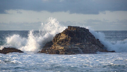Fototapeta na wymiar Waves breaking around rocks just off the beach in Zipolite, Mexico