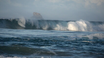 Waves breaking on the beach, with a small, rocky islet just off the coast, in Zipolite, Mexico