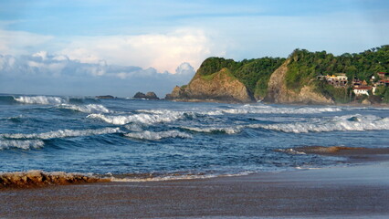 Waves breaking on the beach, with a rocky point in the background, in Zipolite, Mexico