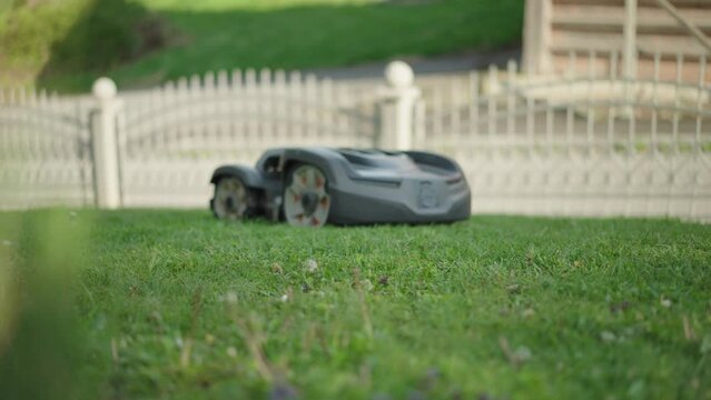 Slow motion shot - Robotic lawn mower trimming the grass, mowing it twice a day, everyday.