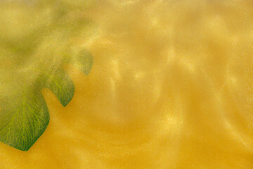 monstera leaf on Yellow Golden Shiny Abstract Background. Paints, Acrylic, Glitter in Water