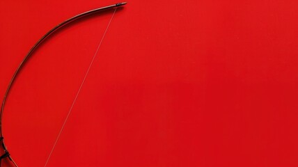 A black recurve bow against a vibrant red background with ample copy space.