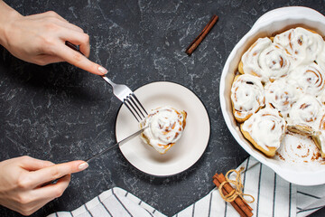Woman's hands cut the Cinnamon rolls or cinnabon, homemade recipe of sweet traditional dessert buns. Top view