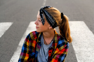 Portrait of a teenage girl wearing a stylish bandana and a cheerful smile, standing confidently on...