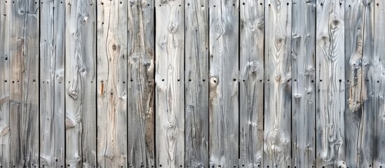 Vertical wooden fence made from rough grey planks with cracks, nails, and scratches. Old horizontal wood texture.