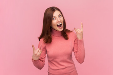 Delighted overjoyed woman showing rock and roll hand sign and yelling, looking crazy aggressive...