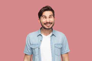 Portrait of hilarious crazy bearded man in casual style shirt standing crosses eyes, makes funny...