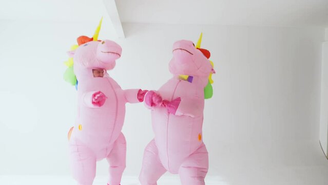 Playful Dance by Two Individuals in Unicorn Costumes With Rainbow Manes