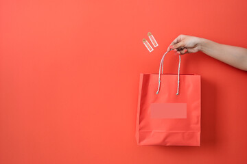 Close-up shot of hand presenting shopping bag on a vibrant coral isolated solid background, promoting vibrant shopping culture, - obrazy, fototapety, plakaty
