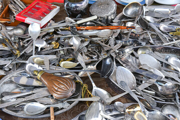 Set of silver and metal spoons and forks in a pile on flea market